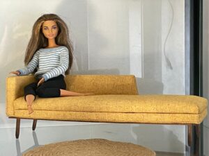 Barbie sentada en sofá color mostaza