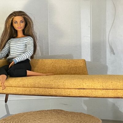 Barbie sentada en sofá color mostaza