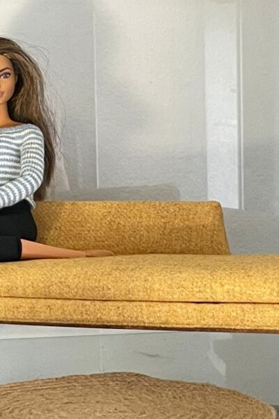 Barbie sentada en sofá color mostaza