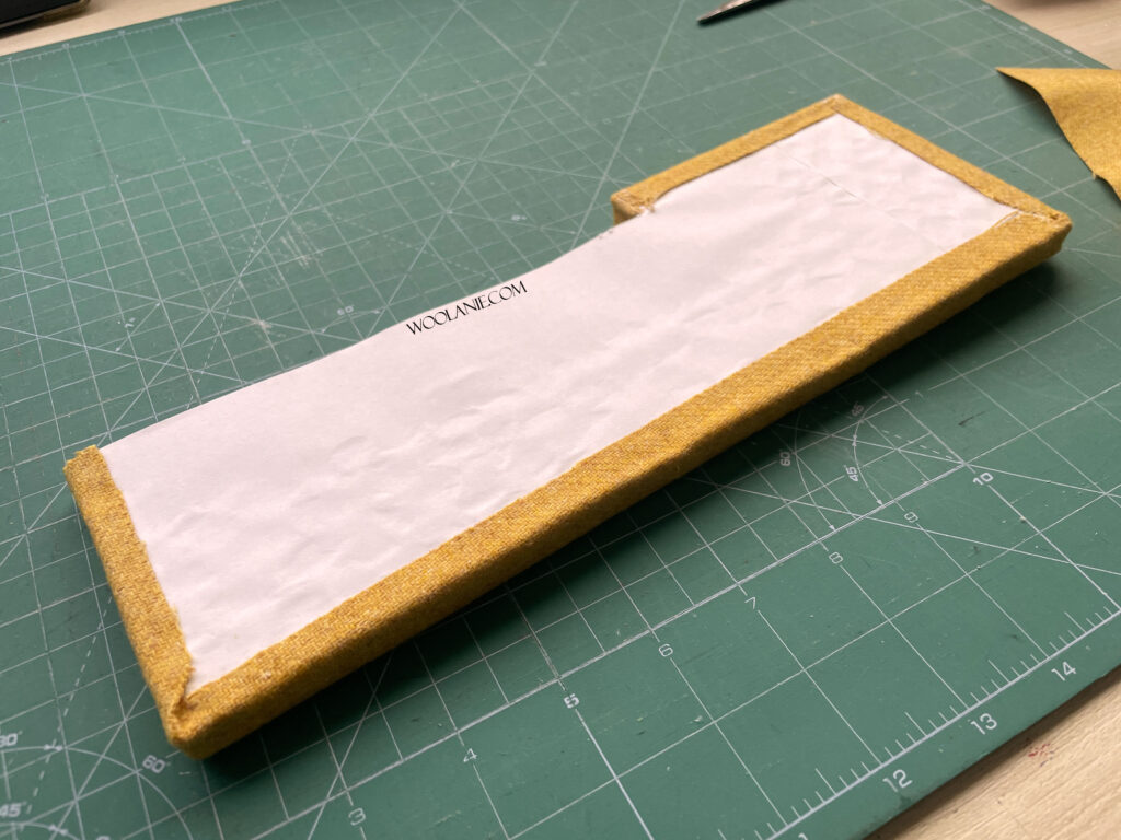 Estructura del sofá en miniatura cubierta con tela, sin guata, mostrando laterales.