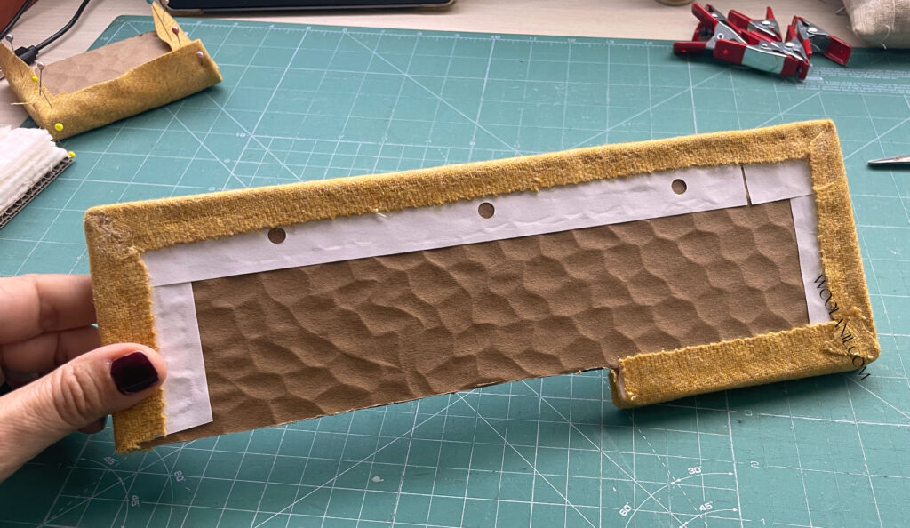 Estructura del sofá en miniatura cubierta con tela, sin guata, mostrando laterales.