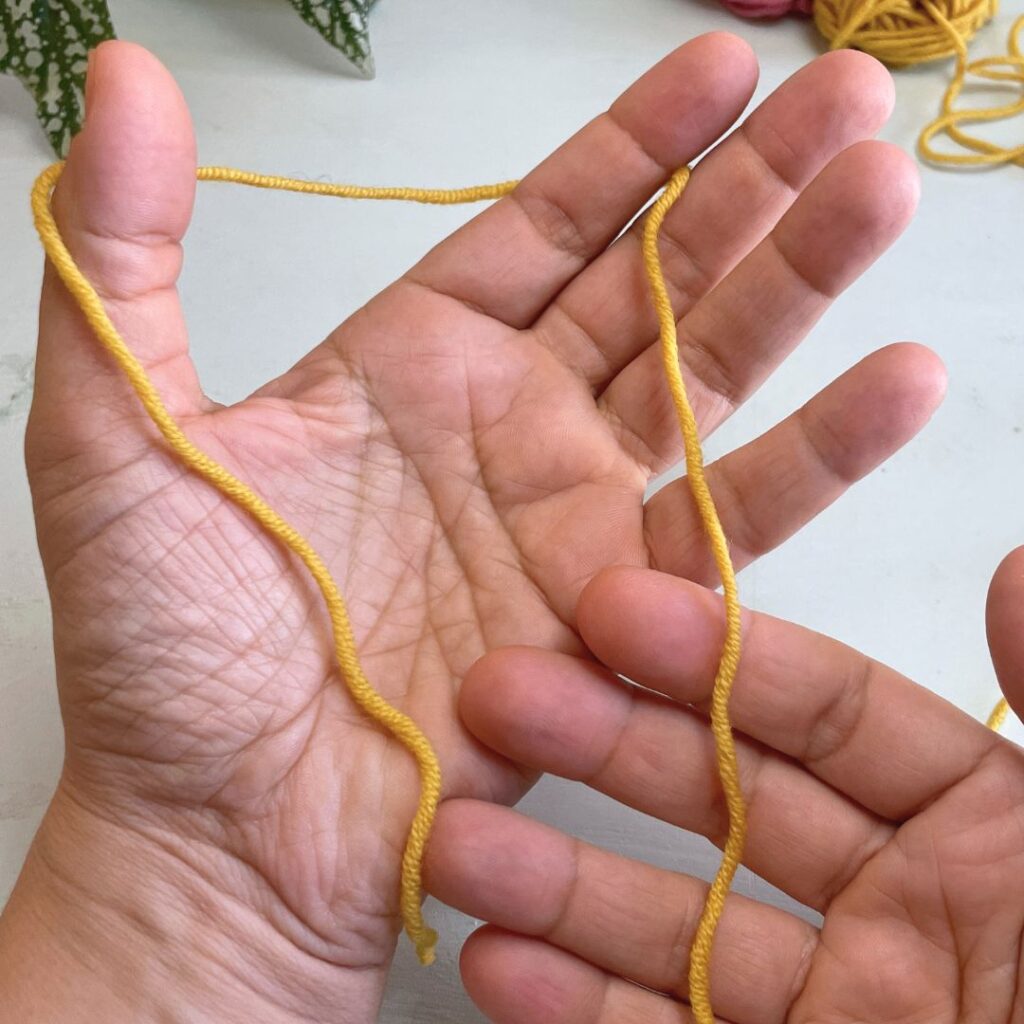 Tercer paso para el montaje de hebra larga: pasar la hebra por detrás del dedo indice