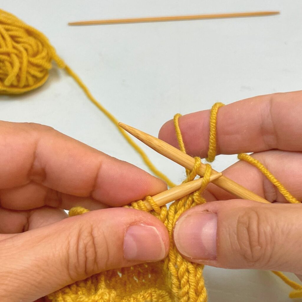 Introduce la aguja izquierda en el primer punto tejido de la aguja derecha