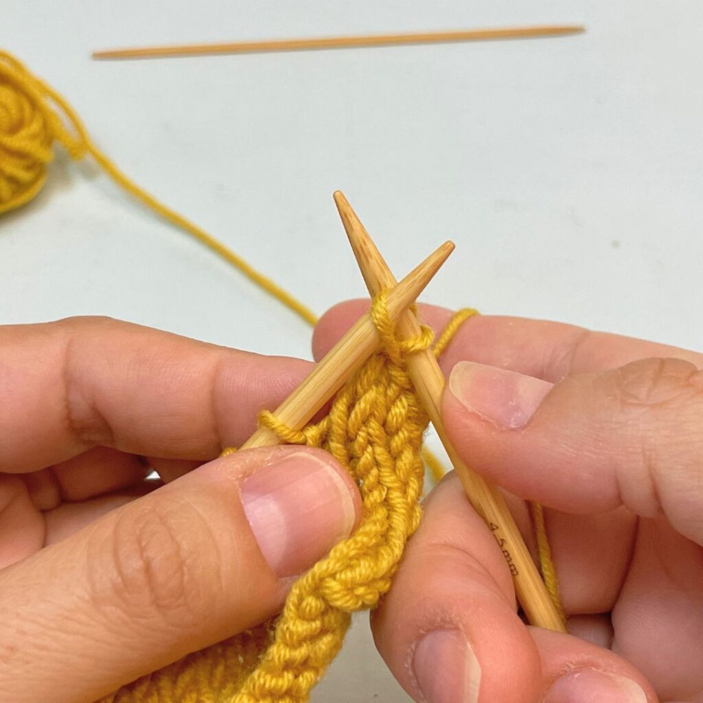 Desliza el primer punto tejido por encima del segundo y arrástralo