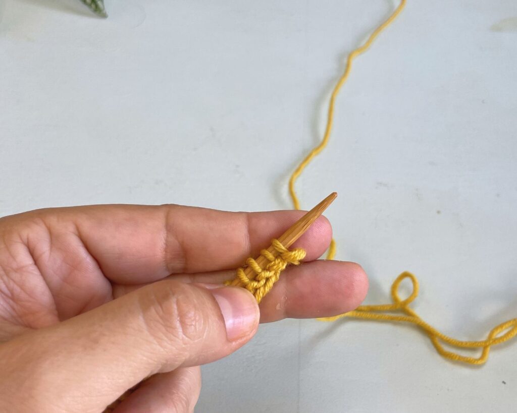 Sujetar la hebra entre los dedos de la mano izquierda antes de comenzar a tejer