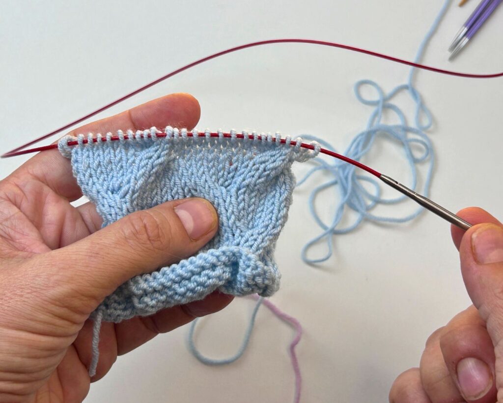 Sacar un poco la aguja y dejar reposar los puntos sobre el cable de las circulares para facilitar pasar la aguja lanera